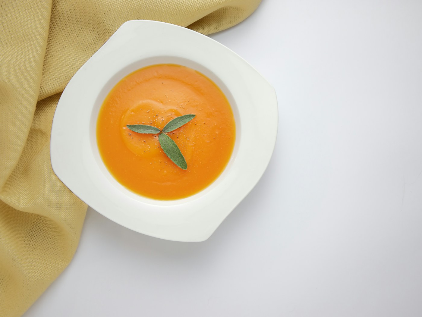 Taça de sopa de cenoura com uma folha de salva